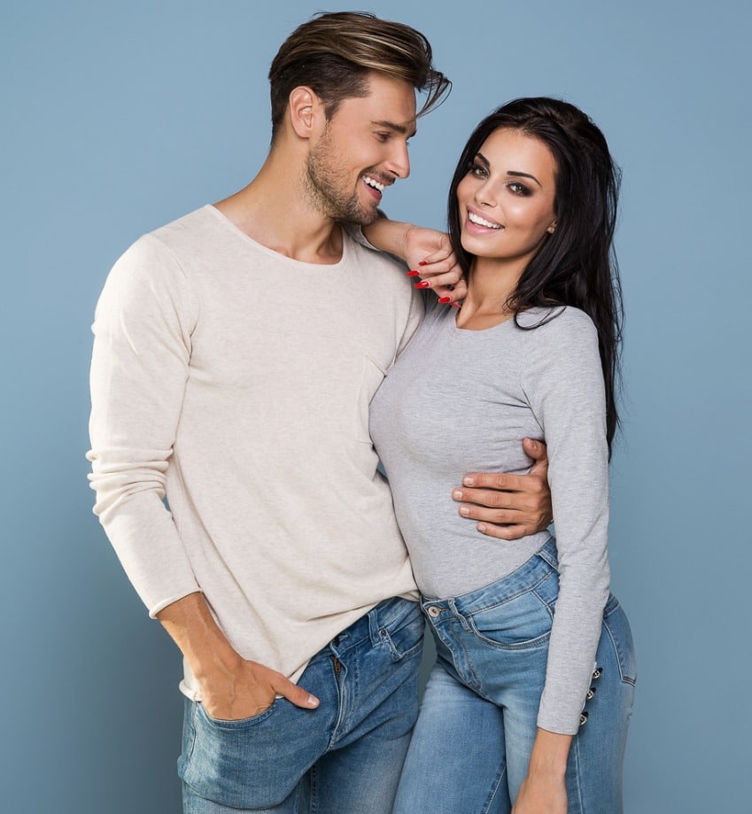 beautiful couple wearing white tee shirts and jeans against a light blue background